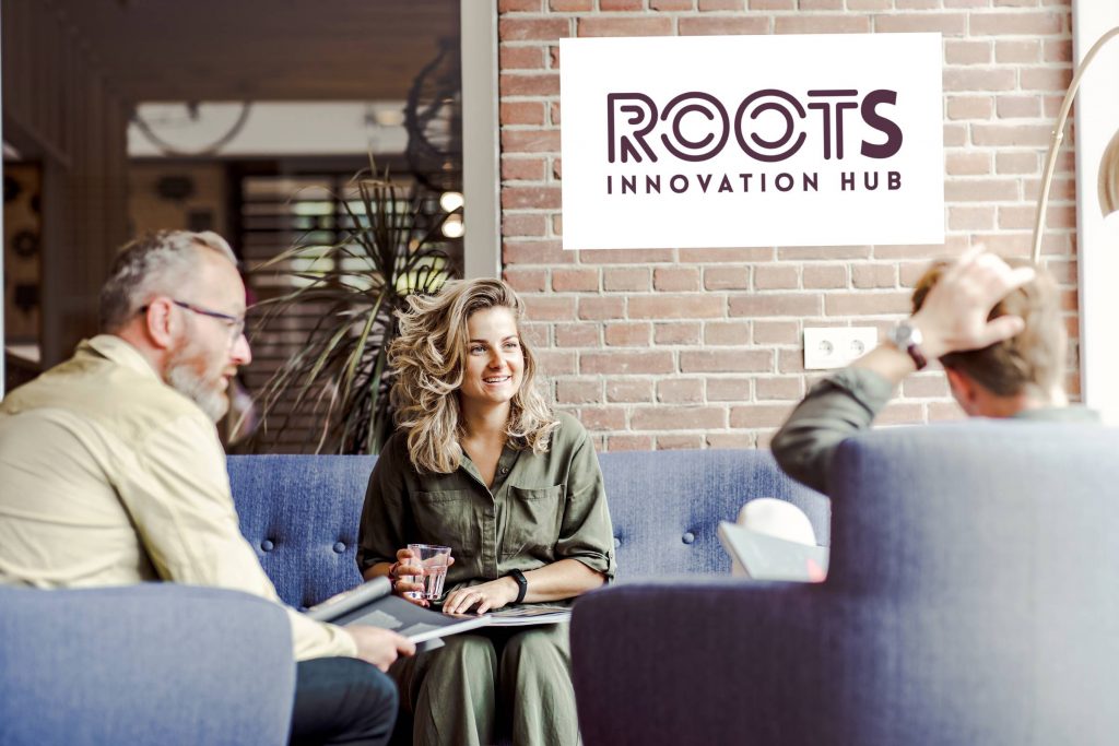 3 personen op sofa's met op de achtergrond een bord met de tekst 'Roots Innovation Hub'