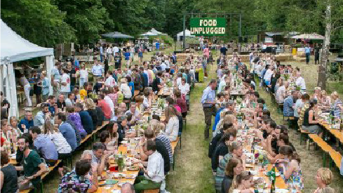 Mensen die met elkaar eten aan lange tafels op de Stormbaan